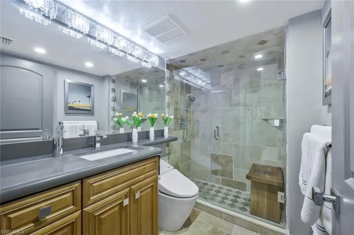 Full bath with visible vents, toilet, a stall shower, and vanity