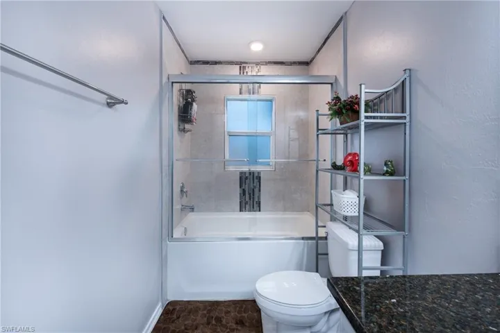 Full bathroom with tile flooring, bath / shower combo with glass door, toilet, and vanity