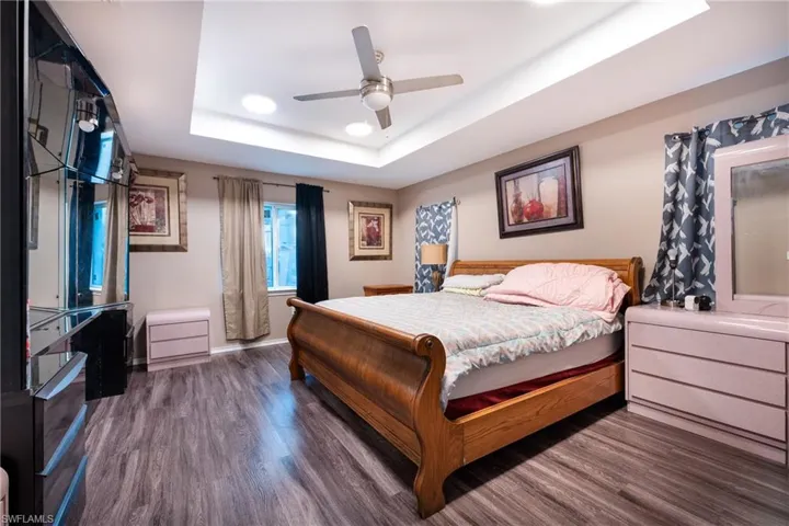 Bedroom with a tray ceiling, ceiling fan, and dark hardwood / wood-style floors