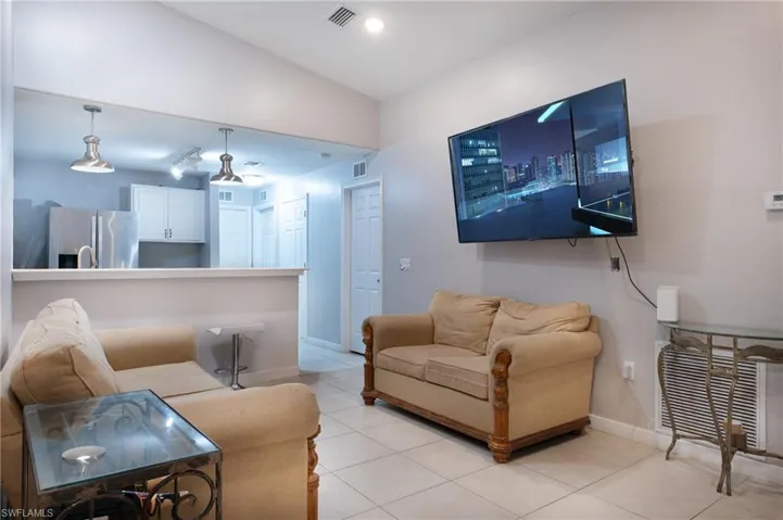 Tiled living room featuring vaulted ceiling