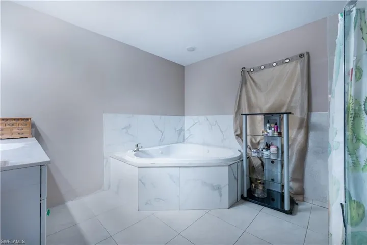 Bathroom with a relaxing tiled bath, tile flooring, and vanity