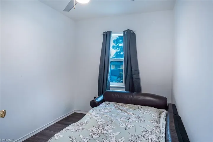 Bedroom with dark hardwood / wood-style flooring, ceiling fan, and multiple windows