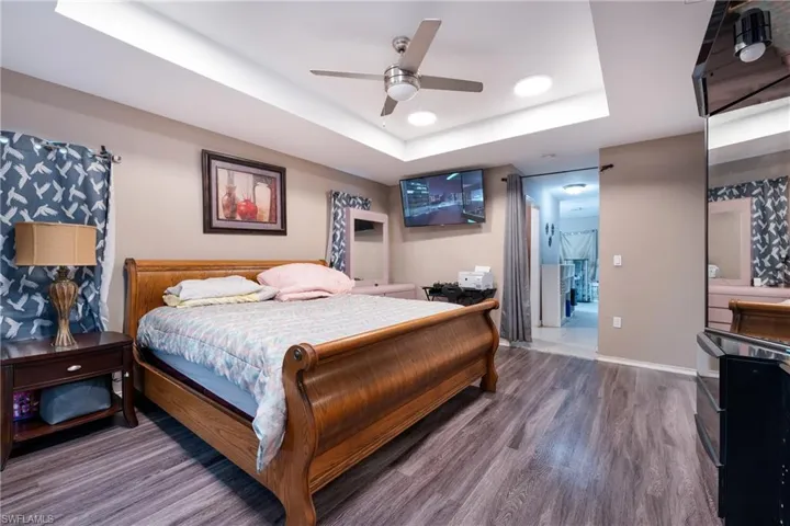 Bedroom featuring wood-type flooring, ceiling fan, and a raised ceiling