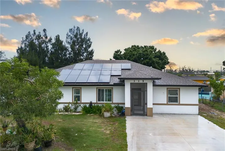 View of front of house with solar panels and a yard