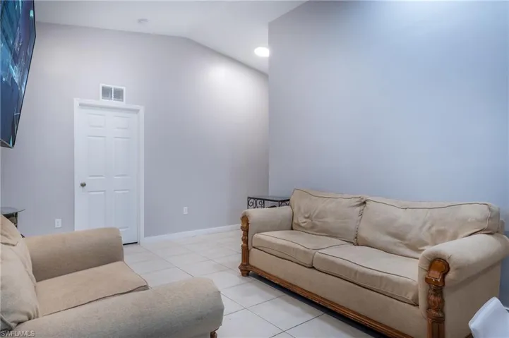 Living room with vaulted ceiling and light tile flooring