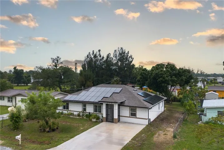 View of front of home with a lawn and solar panels