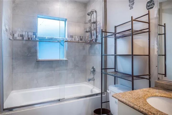 Full bathroom featuring enclosed tub / shower combo, vanity, and toilet