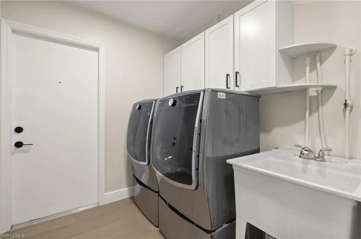 Washroom with separate washer and dryer, cabinet space, and light wood-style flooring