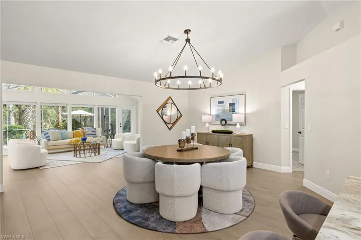 Dining room with a chandelier, wood finished floors, and high vaulted ceiling