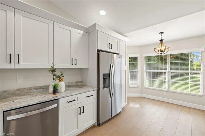 Kitchen featuring stainless steel appliances, white cabinets, light wood-type flooring, hanging light fixtures, and recessed lighting