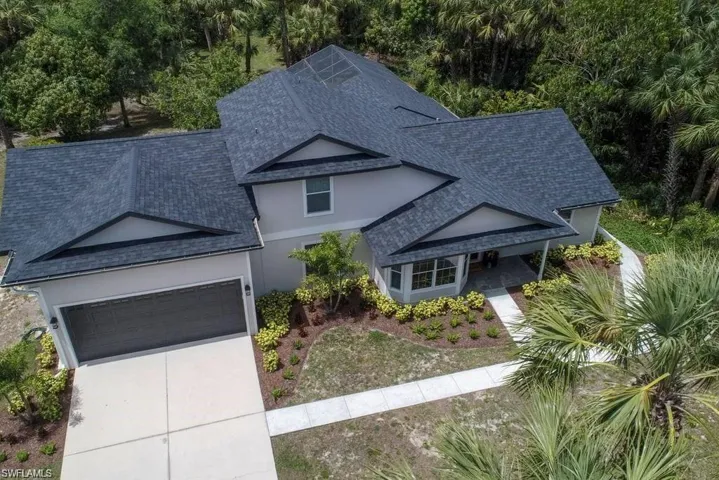 Traditional-style house featuring roof with shingles, a garage, driveway, and stucco siding