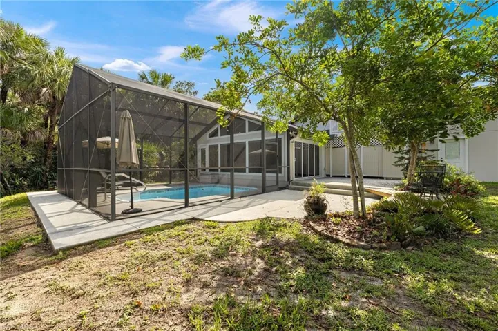Swimming pool with a patio area and a screened lanai, outdoor toilet and shower behind the doors.