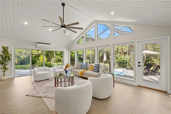 Sunroom/ living room featuring an AC wall unit, hardwood / wood-style floors, high vaulted ceiling, and recessed lighting