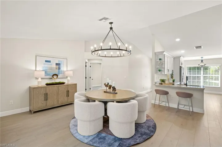 Dining area featuring a chandelier, light wood-style flooring, vaulted ceiling, and recessed lighting