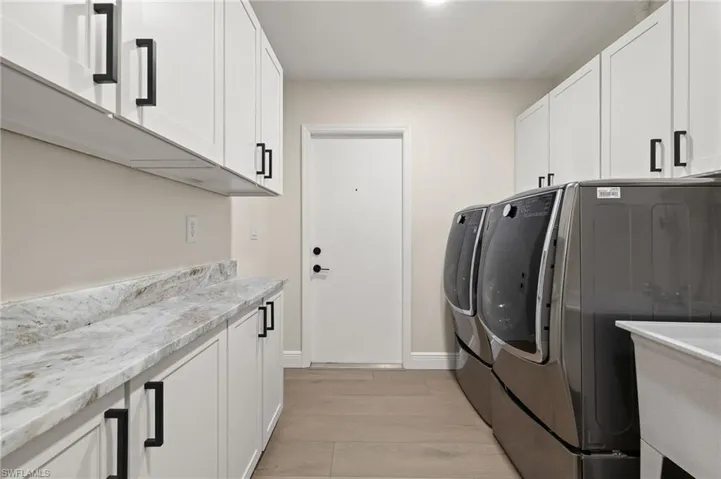 Laundry area with washer and dryer, cabinet space, and light wood-type flooring