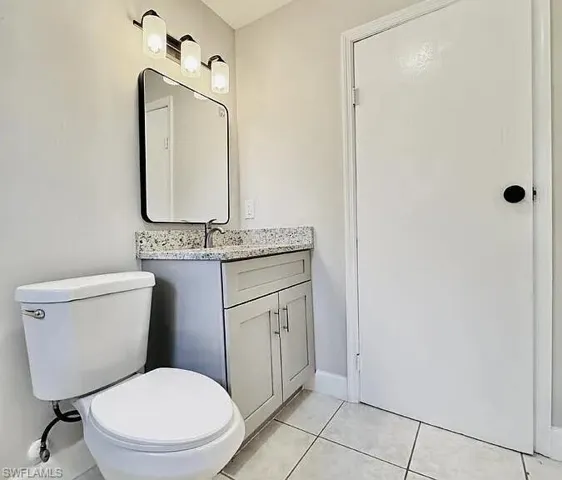 Vanity with a light gray cabinet, granite-look countertop, and rectangular mirror