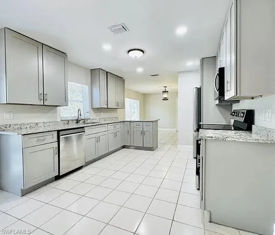 Kitchen featuring light gray cabinetry, stainless steel appliances, granite countertops, and white tile flooring