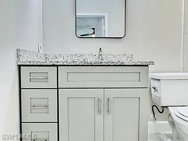 Vanity featuring a light gray finish, polished chrome hardware, and a granite-look countertop
