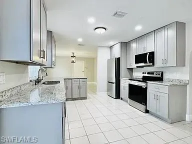 Kitchen featuring light gray cabinetry, stainless steel appliances, a center island, granite countertops, and tile flooring
