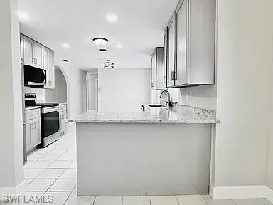 Kitchen featuring light-toned cabinetry, stainless steel appliances, speckled countertops, and tile flooring