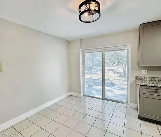 Recessed lighting, tile flooring, sliding glass door, modern ceiling fixture, and base cabinetry with stone countertop
