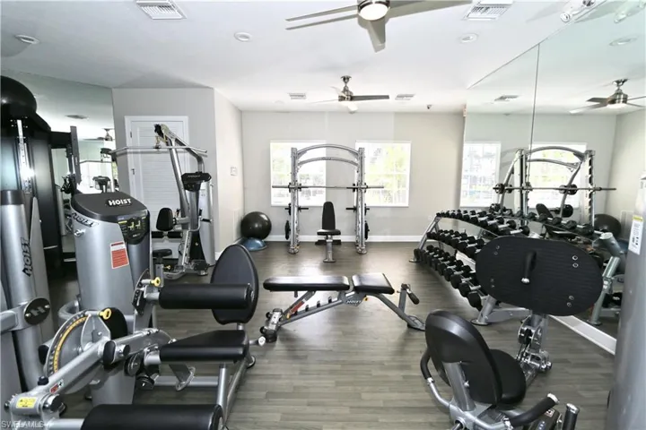 Fitness center featuring wood-finish flooring, recessed lighting, and mirrored walls
