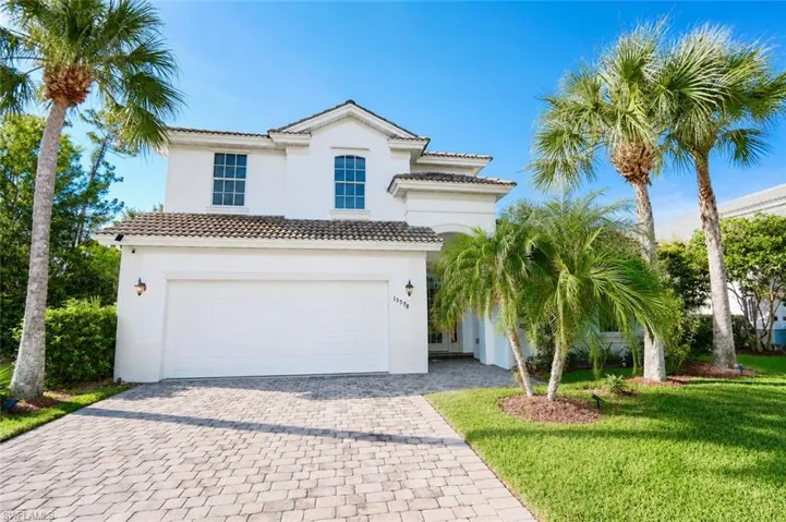 Two-story residence featuring a white stucco exterior, tile roofing, and an integrated two-car garage