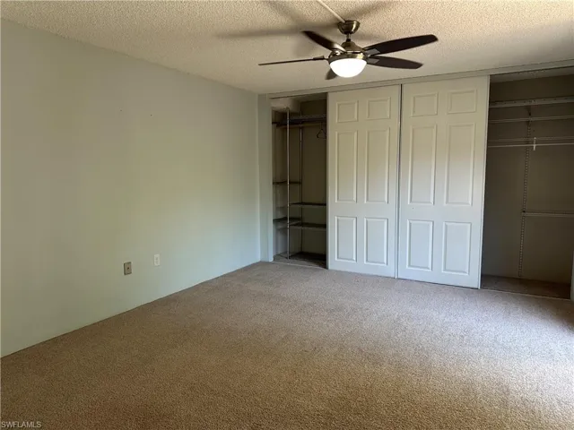 Unfurnished bedroom featuring carpet floors, a textured ceiling, and ceiling fan