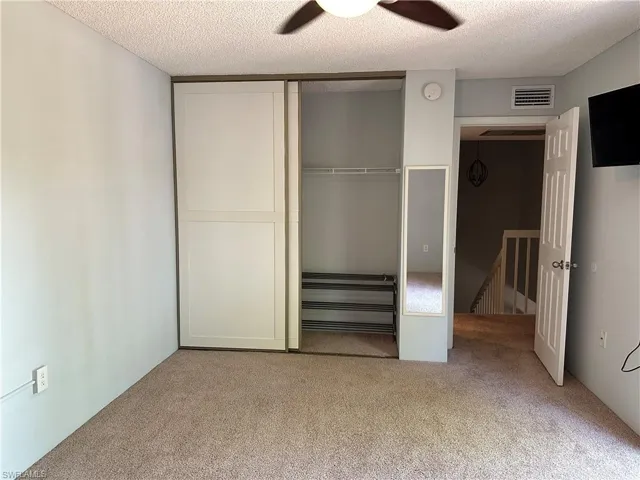 Unfurnished bedroom with carpet, a closet, a textured ceiling, and ceiling fan