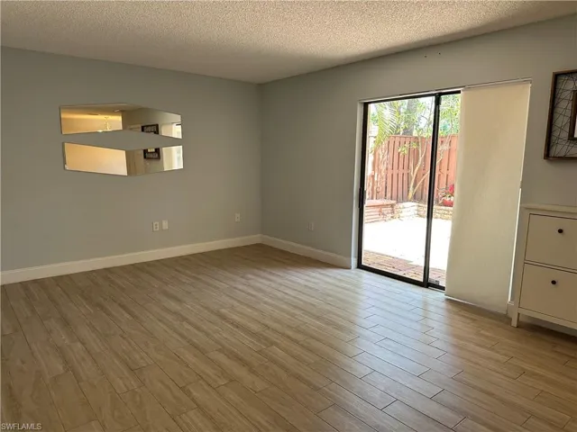 Empty room with wood finished floors, a textured ceiling, baseboards, and arched walkways