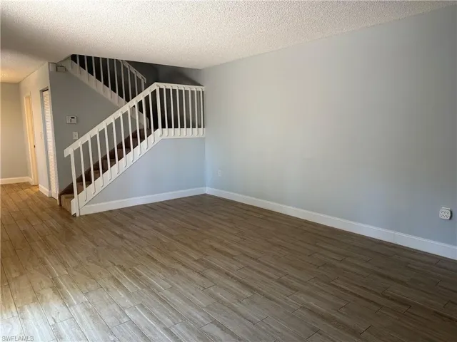 Spare room with wood finished floors, baseboards, stairs, and a textured ceiling
