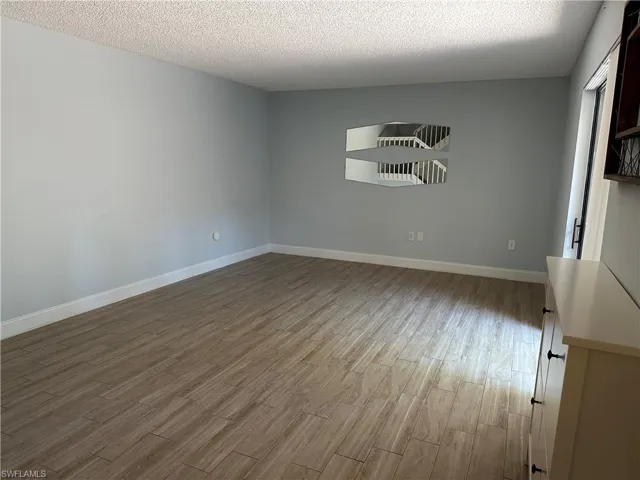 Spare room with wood finished floors, baseboards, and a textured ceiling