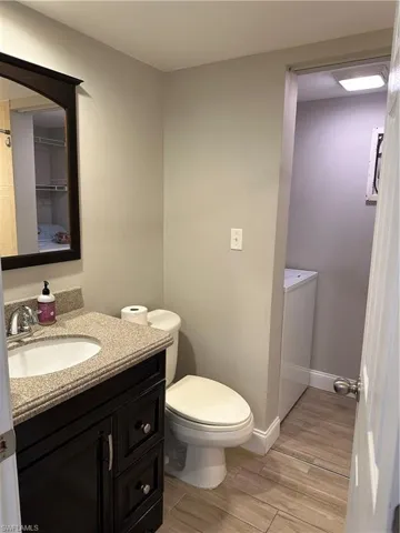 Bathroom featuring wood tiled floors, vanity, toilet, and baseboards