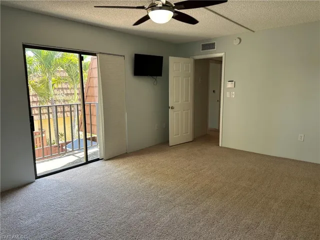 Unfurnished bedroom with access to exterior, carpet floors, a textured ceiling, and a ceiling fan