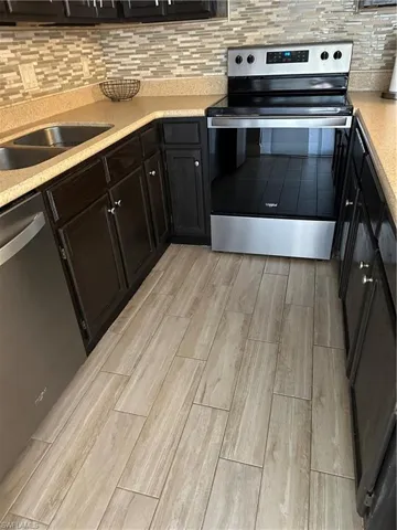 Kitchen featuring stove, wood finish floors, dishwashing machine, and light countertops