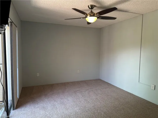 Spare room featuring carpet, a ceiling fan, and a textured ceiling