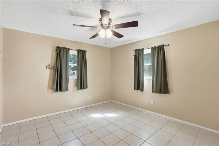 Empty room featuring a ceiling fan, a textured ceiling, and light tile patterned flooring
