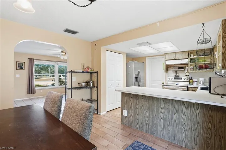 Kitchen with light countertops, stainless steel appliances, arched walkways, open shelves, and a peninsula