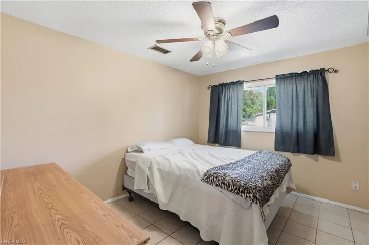 Bedroom with ceiling fan, a textured ceiling, and light tile patterned floors