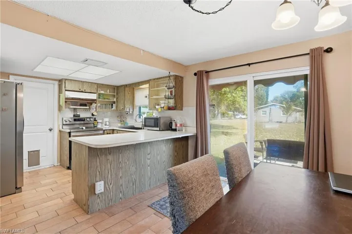 Kitchen featuring stainless steel appliances, light countertops, a peninsula, open shelves, and backsplash