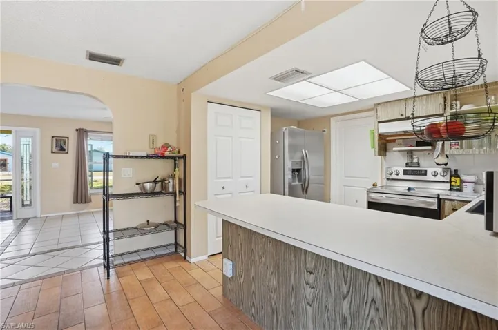 Kitchen featuring arched walkways, light countertops, stainless steel appliances, wood tiled floors, and a peninsula
