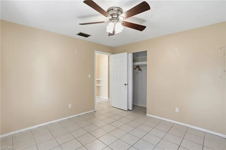 Unfurnished bedroom featuring a closet, ceiling fan, a textured ceiling, and light tile patterned flooring