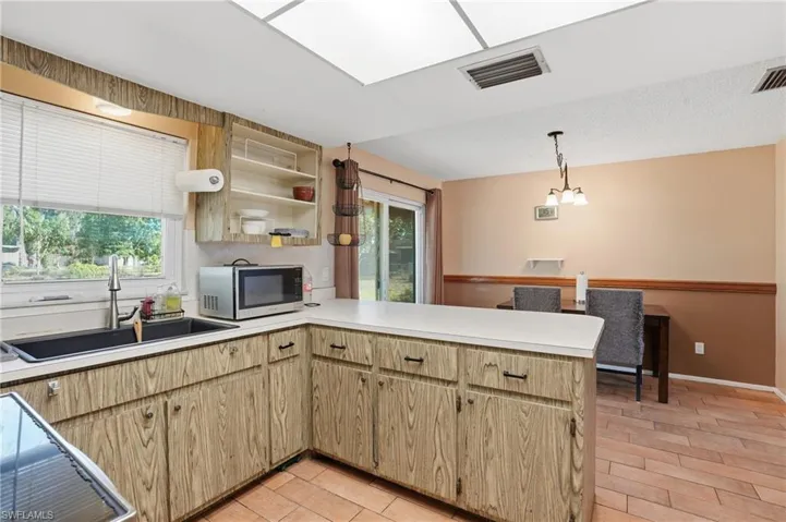 Kitchen with a peninsula, light countertops, open shelves, and light wood finish cabinets