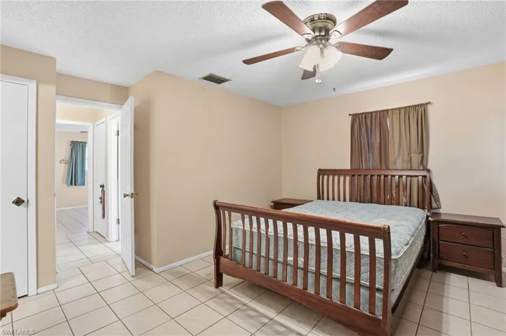 Bedroom featuring ceiling fan, a textured ceiling, and light tile patterned flooring