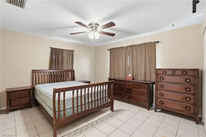 Bedroom featuring a ceiling fan, a textured ceiling, and light tile patterned flooring