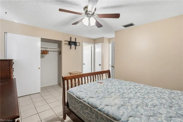 Bedroom featuring a textured ceiling, light tile patterned flooring, a closet, and a ceiling fan