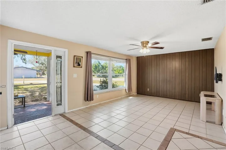 Unfurnished living room with wood walls, a ceiling fan, a textured ceiling, and light tile patterned flooring