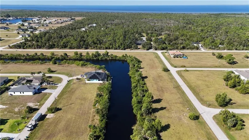 Aerial overview of property's location with a nearby body of water and a forest