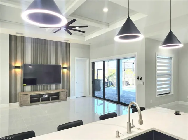 Kitchen with coffered ceiling, pendant lighting, ceiling fan, light stone countertops, and beamed ceiling