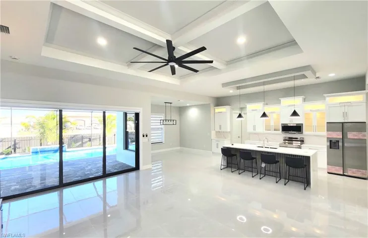 Kitchen featuring appliances with stainless steel finishes, a kitchen breakfast bar, white cabinets, hanging light fixtures, and coffered ceiling